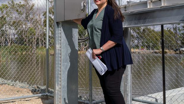 Harriet Shing with dark hair and glasses stands on top of a fishway near Gunbower Creek. 