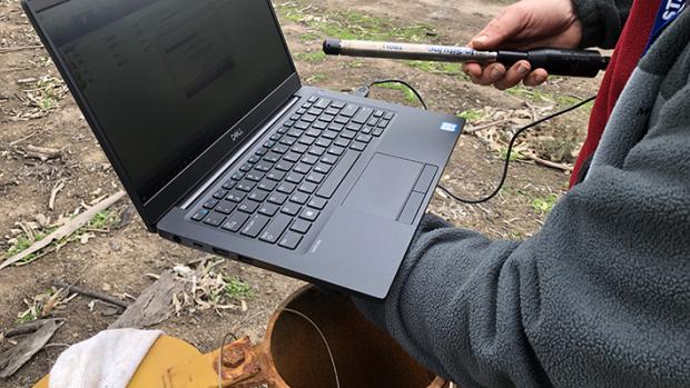 Computer and logger measuring deep into a yellow water bore